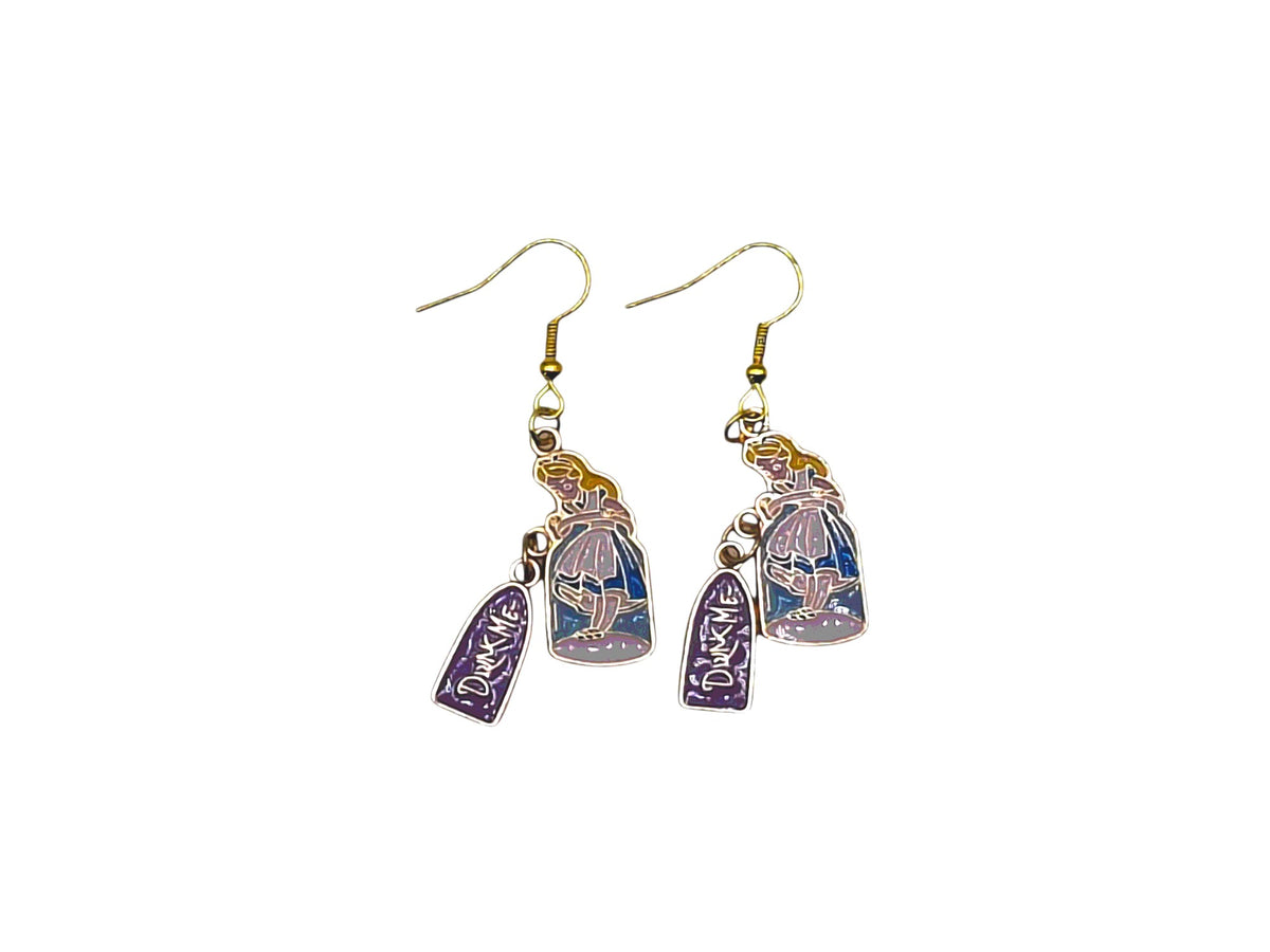 Boucles d’oreilles Alice fiole Drink Me bleue et violette avec crochets dorés sur fond blanc