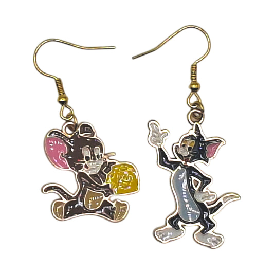 Boucles d’oreilles Tom et Jerry en duo dépareillé, Jerry avec fromage et Tom faisant signe, crochets dorés, sur fond blanc