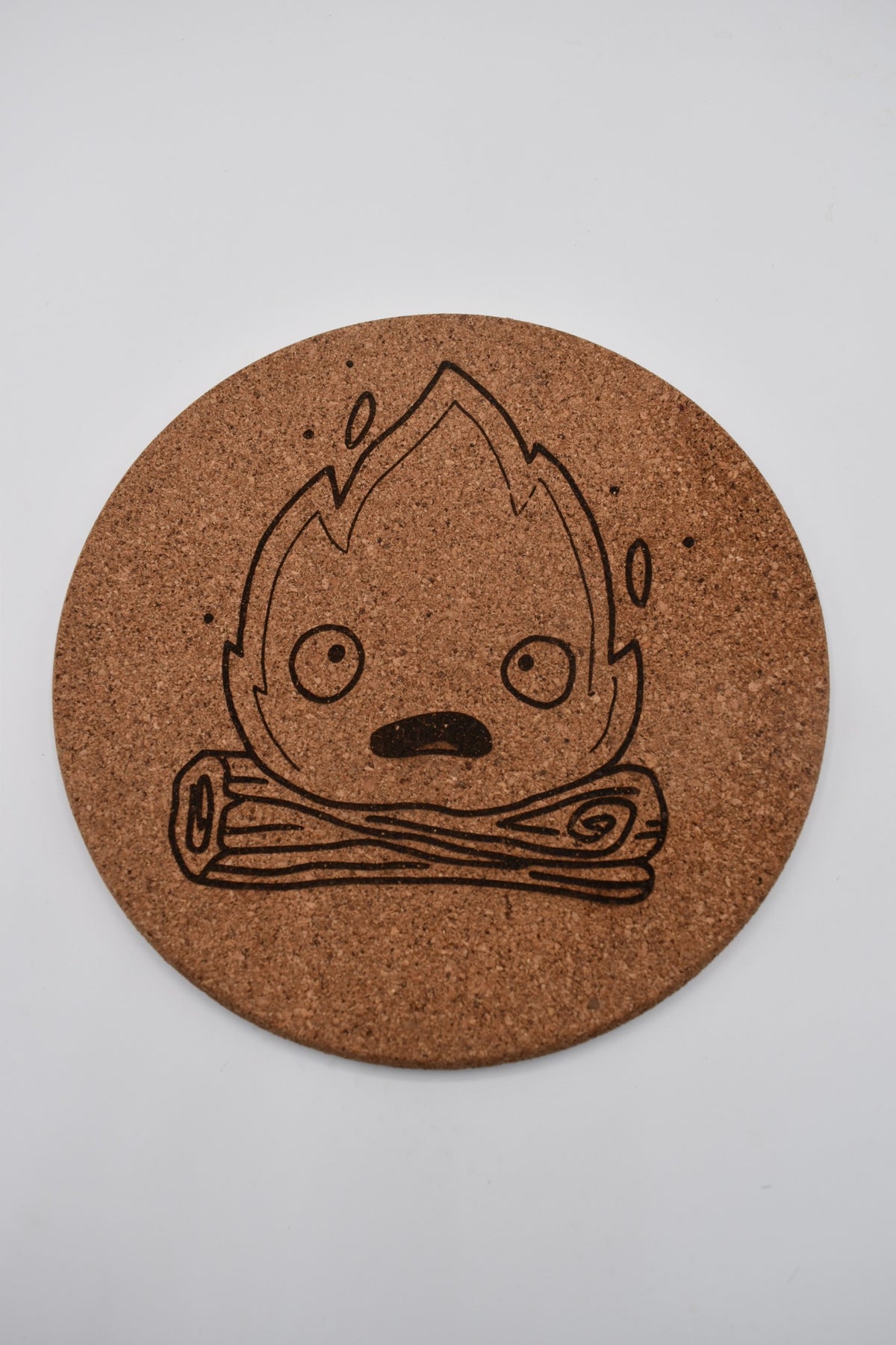 Round cork trivet engraved with a Calcifer design inspired by Howl's Moving Castle